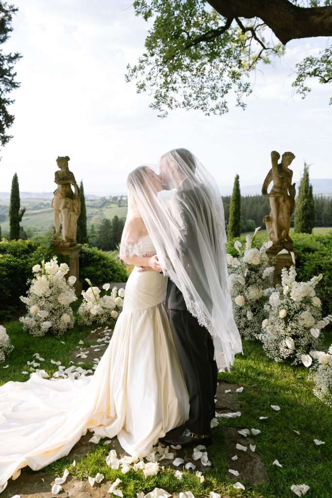 Bride and groom kissing under the veil in a garden in Tuscany